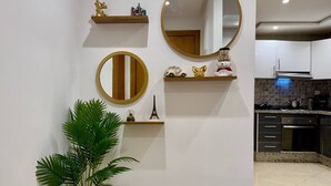 A modern kitchen with white walls, wooden shelves, and decorative items. - Comfort & Style Apartment (Kénitra)