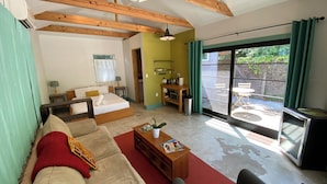 Amplia sala de estar con cama, sofá y una mesa de comedor. Cuenta con una puerta corrediza de vidrio que da a un patio exterior.
