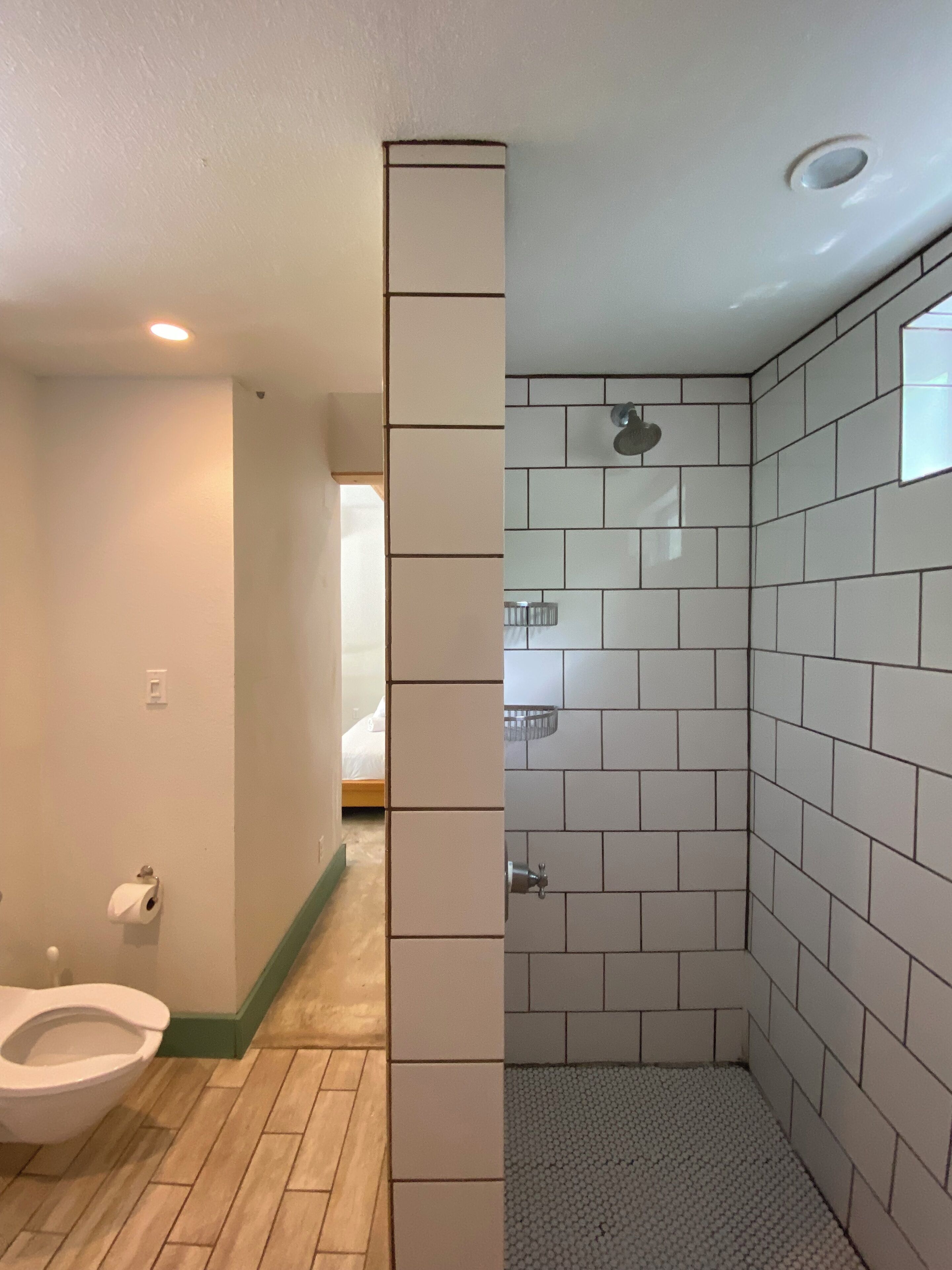 Ein Badezimmer mit Toilette, einer gefliesten Dusche und einem Holzboden.