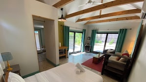 Un dormitorio con cama, techo de madera, ventana con cortinas y vistas al exterior.