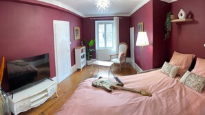 Un dormitorio con una cama, televisión, guitarra, escritorio y una silla.