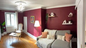 Una sala de estar con un sofá gris, un sillón blanco, una mesa de centro de madera y una araña.