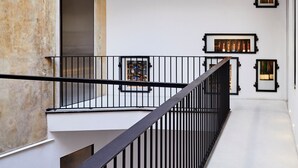 Un intérieur moderne avec un escalier menant à un deuxième étage, agrémenté de rampes noires et d’œuvres d’art encadrées.