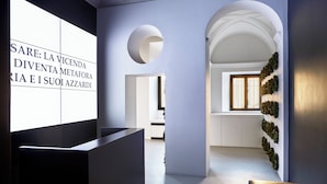 Un intérieur moderne comprenant un comptoir d’accueil, un grand mur orné de texte et un couloir menant à une pièce dotée d’une fenêtre.