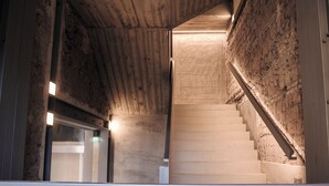 Un escalier avec une rampe en bois et des murs en pierre brute.