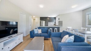 A modern living room with a TV, sofas, and a dining area. - Meridian unit 4 Kings Beach QLD (Kings Beach)