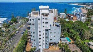 A modern multi-story building with balconies, a swimming pool, and a view of the ocean. - Meridian unit 4 Kings Beach QLD (Kings Beach)