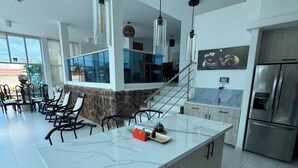 Eine moderne Küche mit einer großen Kochinsel, Edelstahlgeräten und einem Essbereich mit Stühlen und einem Tisch.