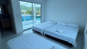 Ein Hotelzimmer mit zwei Betten, einer Schiebetür zu einem Balkon und Blick auf einen Pool und Grünflächen.