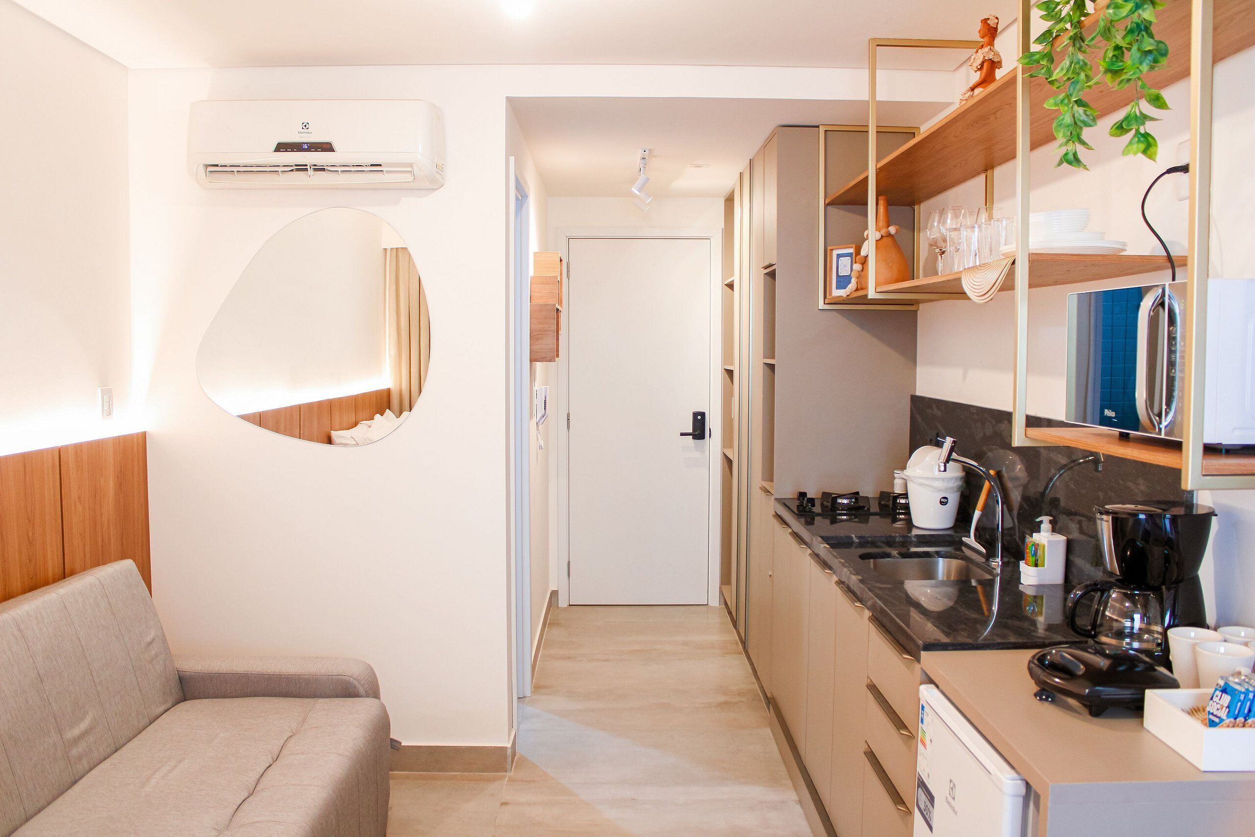 Una cocina compacta con horno integrado, cafetera y microondas.