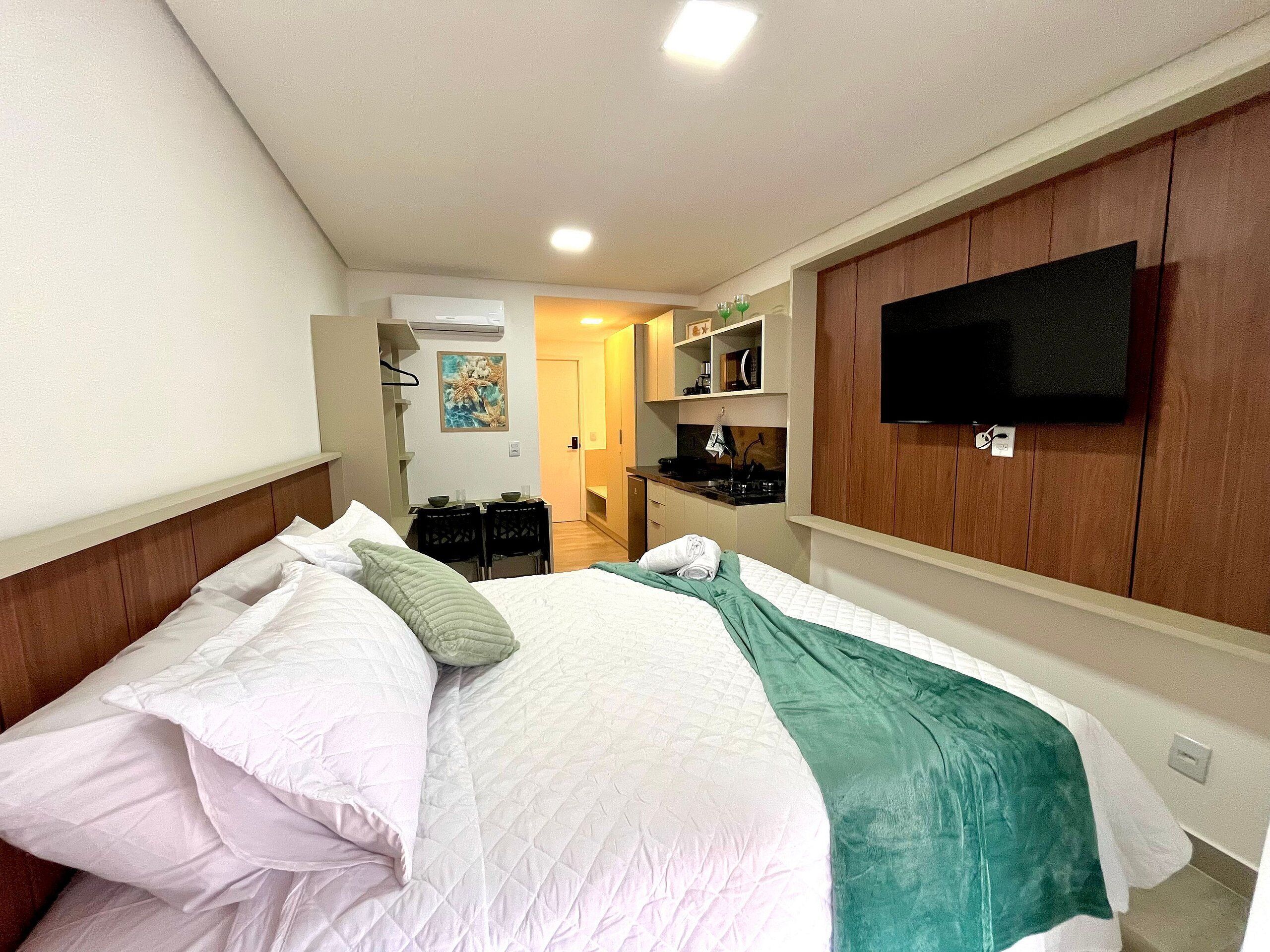 Une chambre d’hôtel comprenant un lit, une télévision, une kitchenette et une salle de bain.