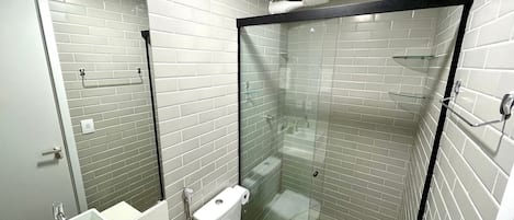 A modern bathroom with a glass-enclosed shower, white subway tiles, and a white sink with a mirror.