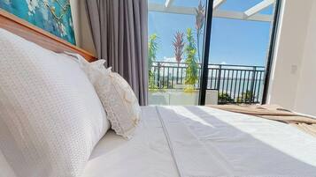 Un dormitorio con una cama grande, vistas al mar y un balcón con plantas.