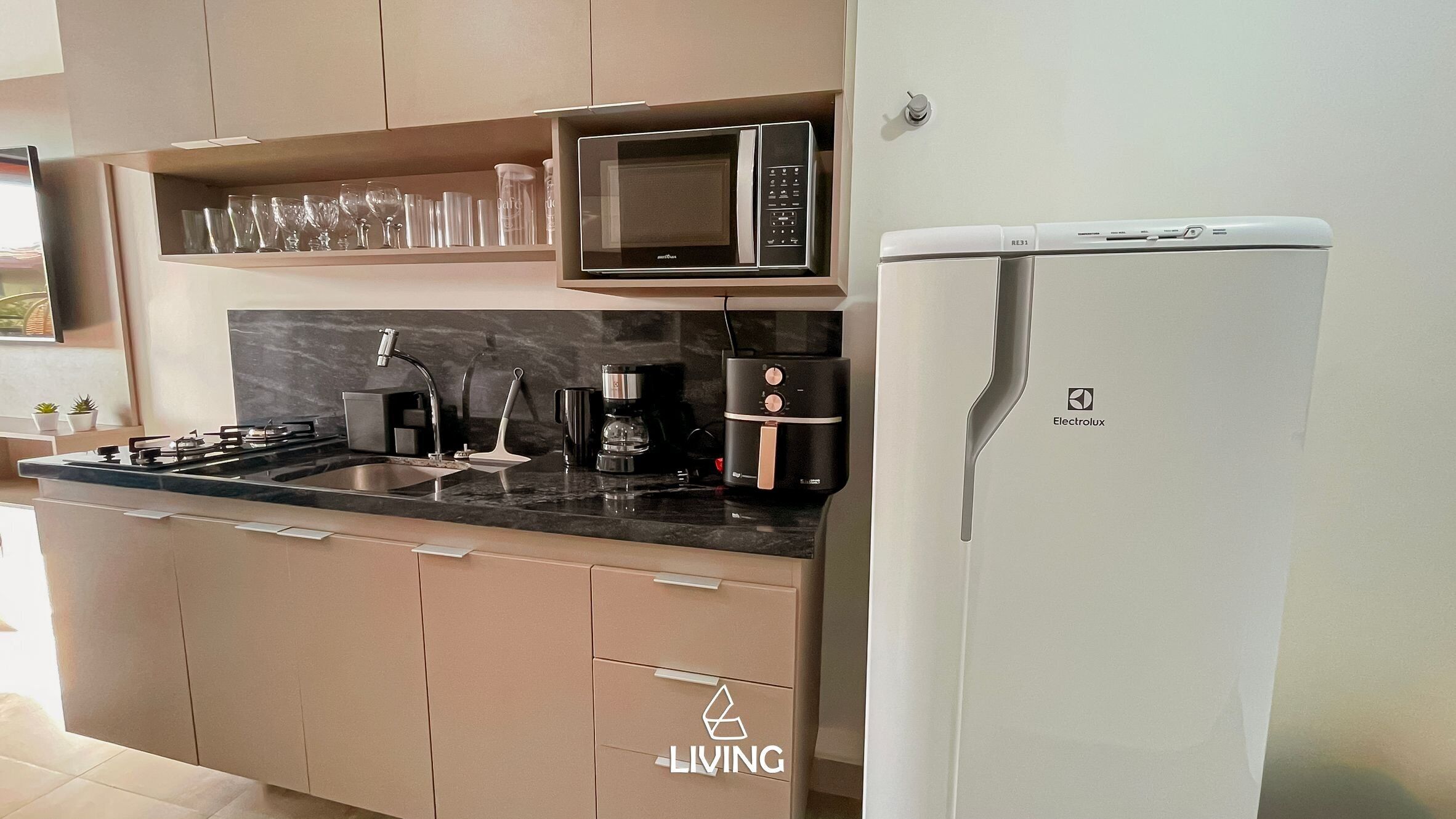 Una cocina moderna con microondas integrado, cafetera y refrigerador.