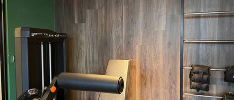 A gym with exercise equipment, a digital clock, and a wooden wall.