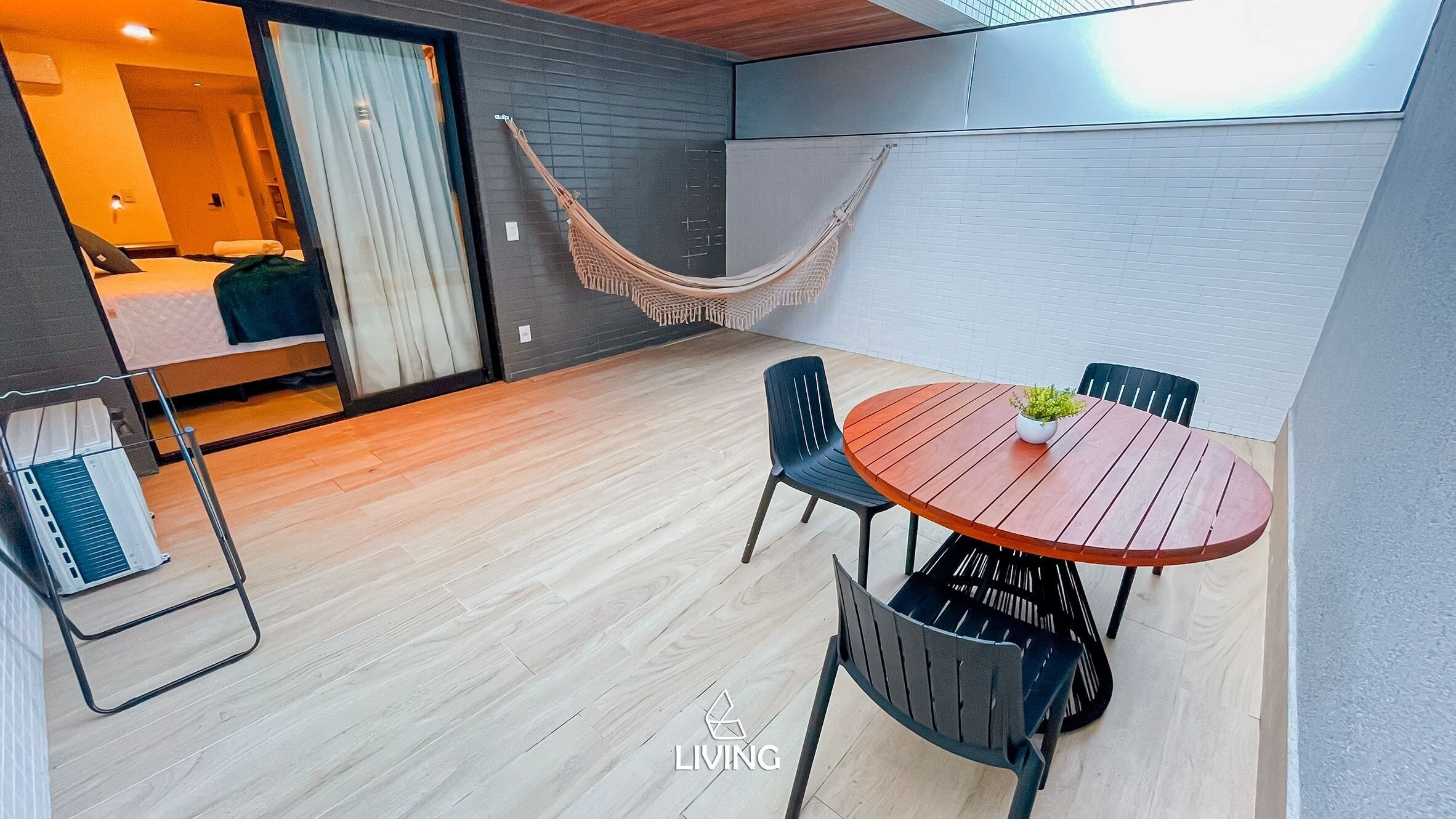 Un patio moderno al aire libre con una mesa y sillas de madera, una hamaca y vistas al interior.