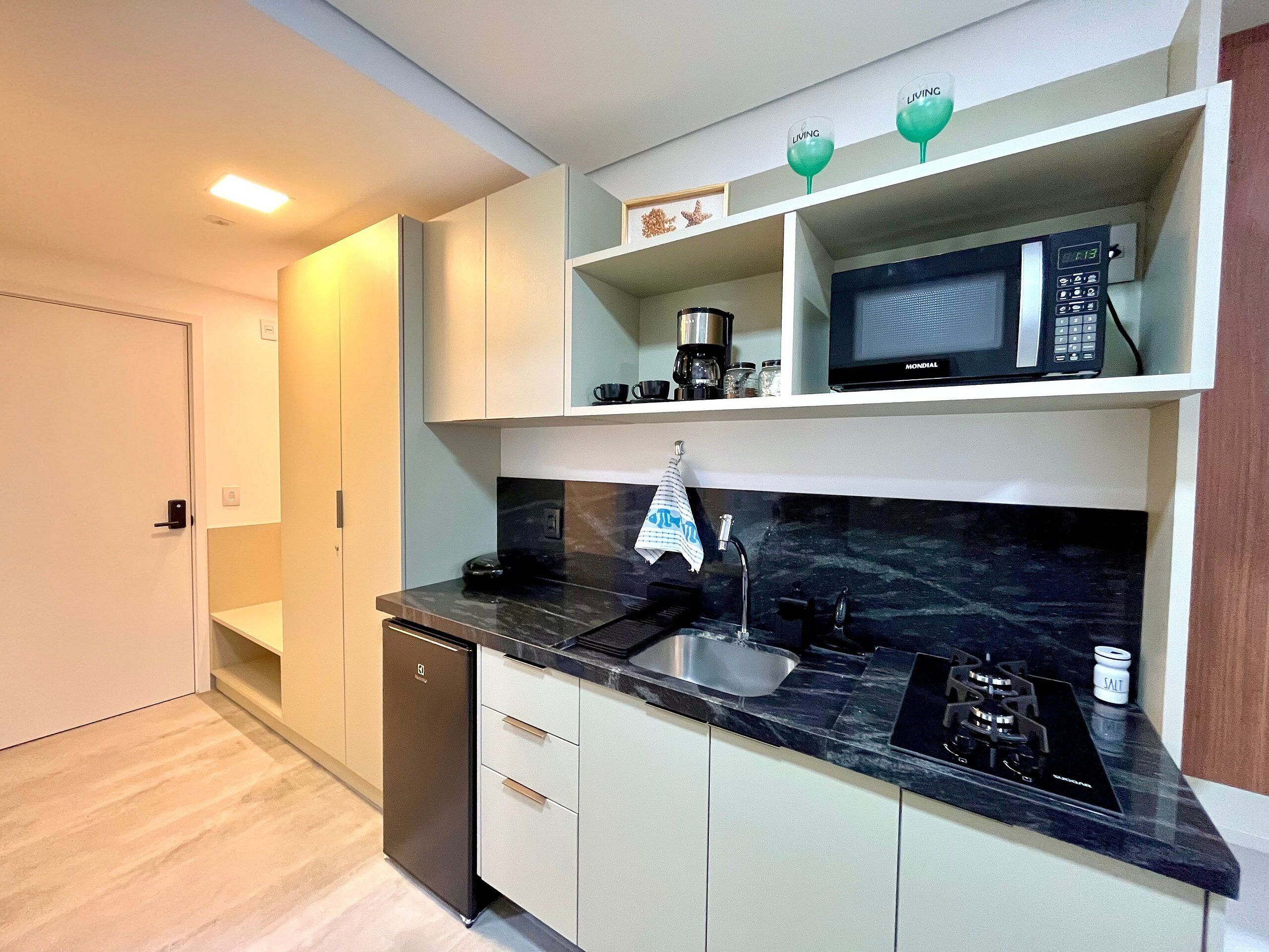 A modern kitchen with a built-in microwave, a coffee maker, and a salt container on the countertop.