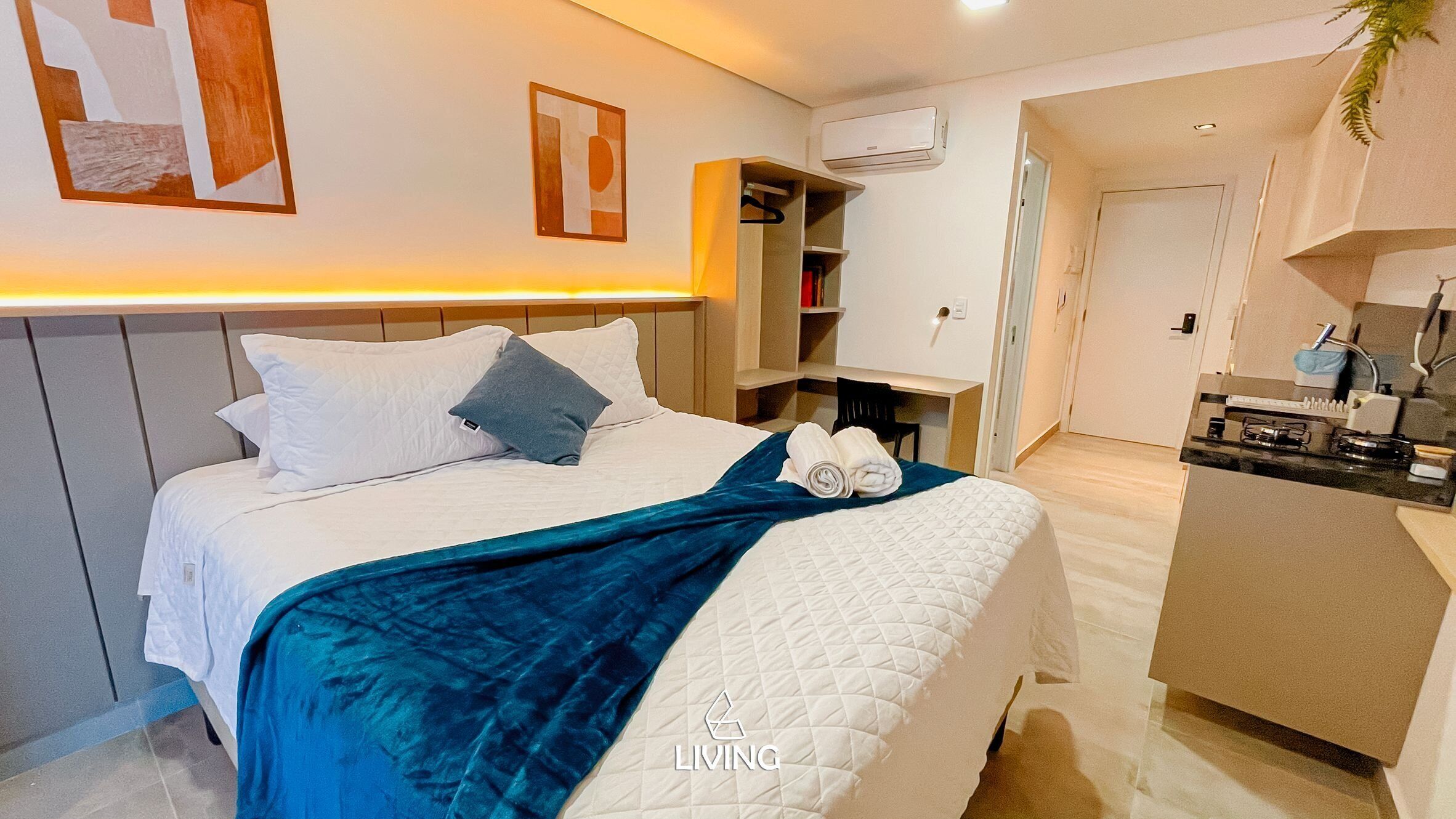 A hotel room with a bed, a desk, a kitchenette, and a wardrobe.