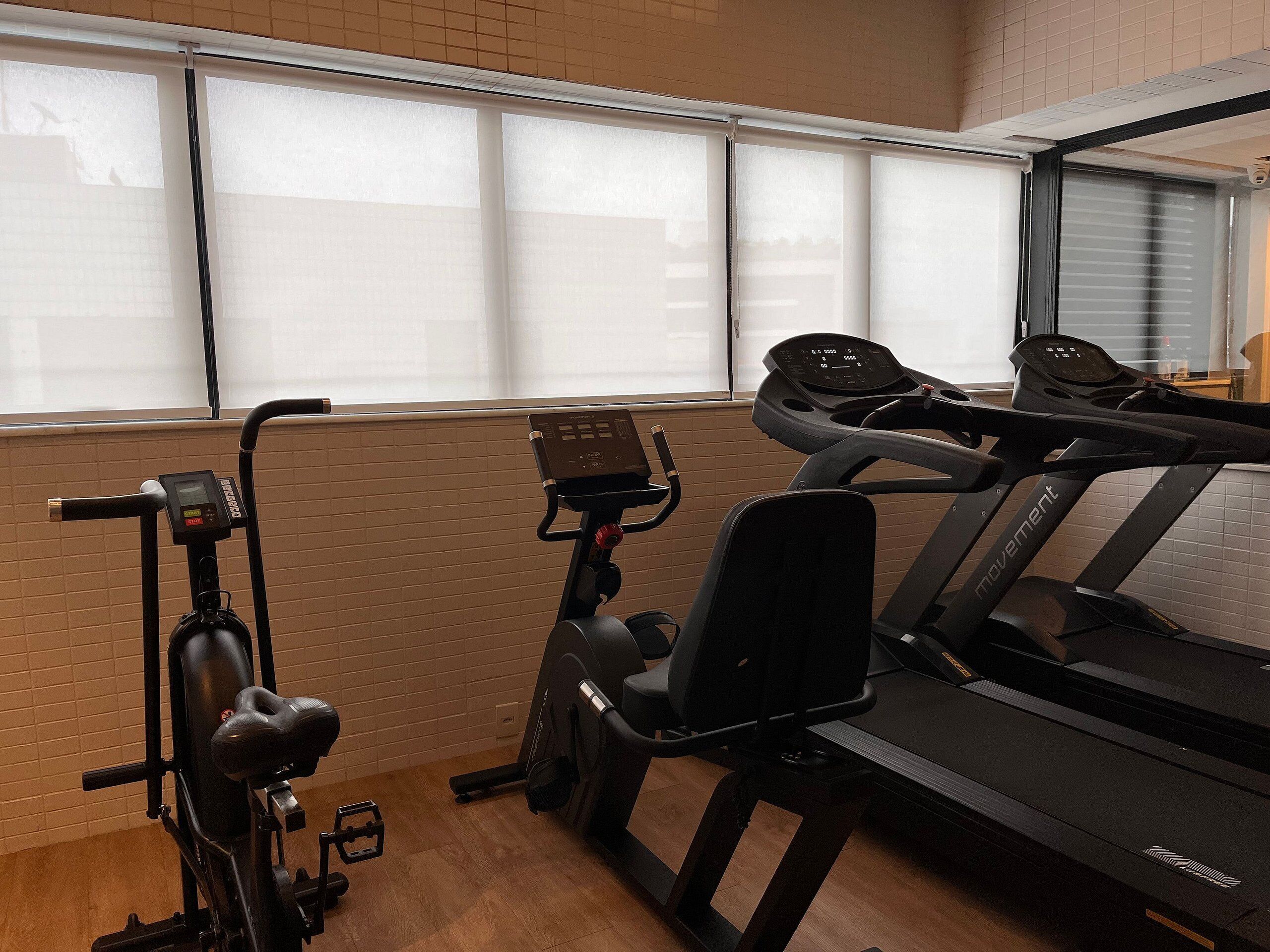 A gym with a treadmill, an elliptical, and a stationary bike.