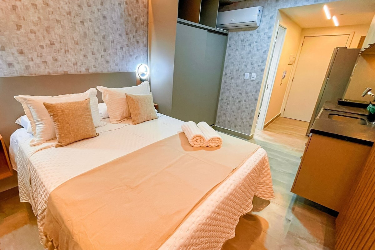 A hotel room with a bed, bedside lamps, a wardrobe, and a kitchenette.