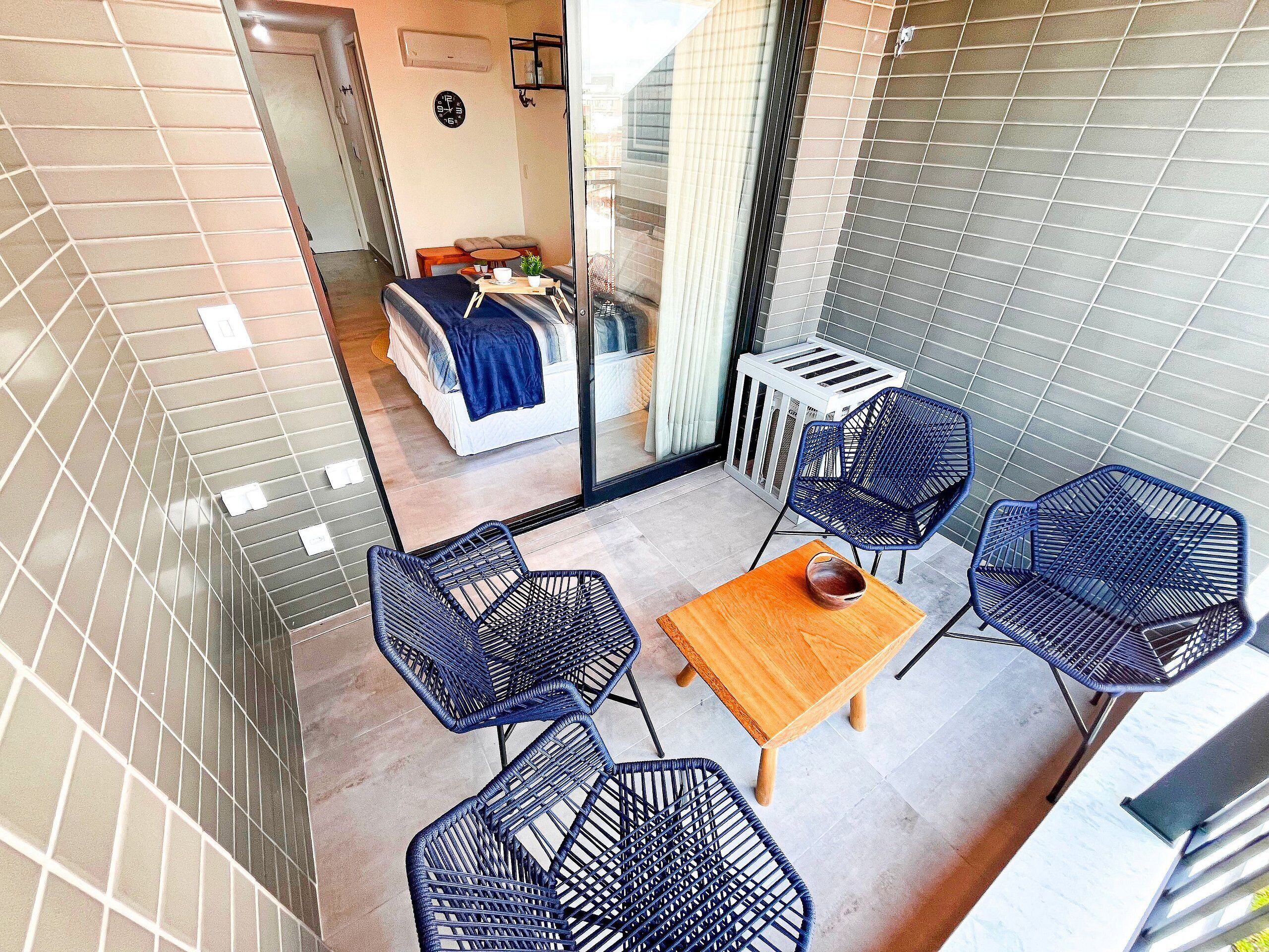 A balcony with a bed, a small table, and four chairs.