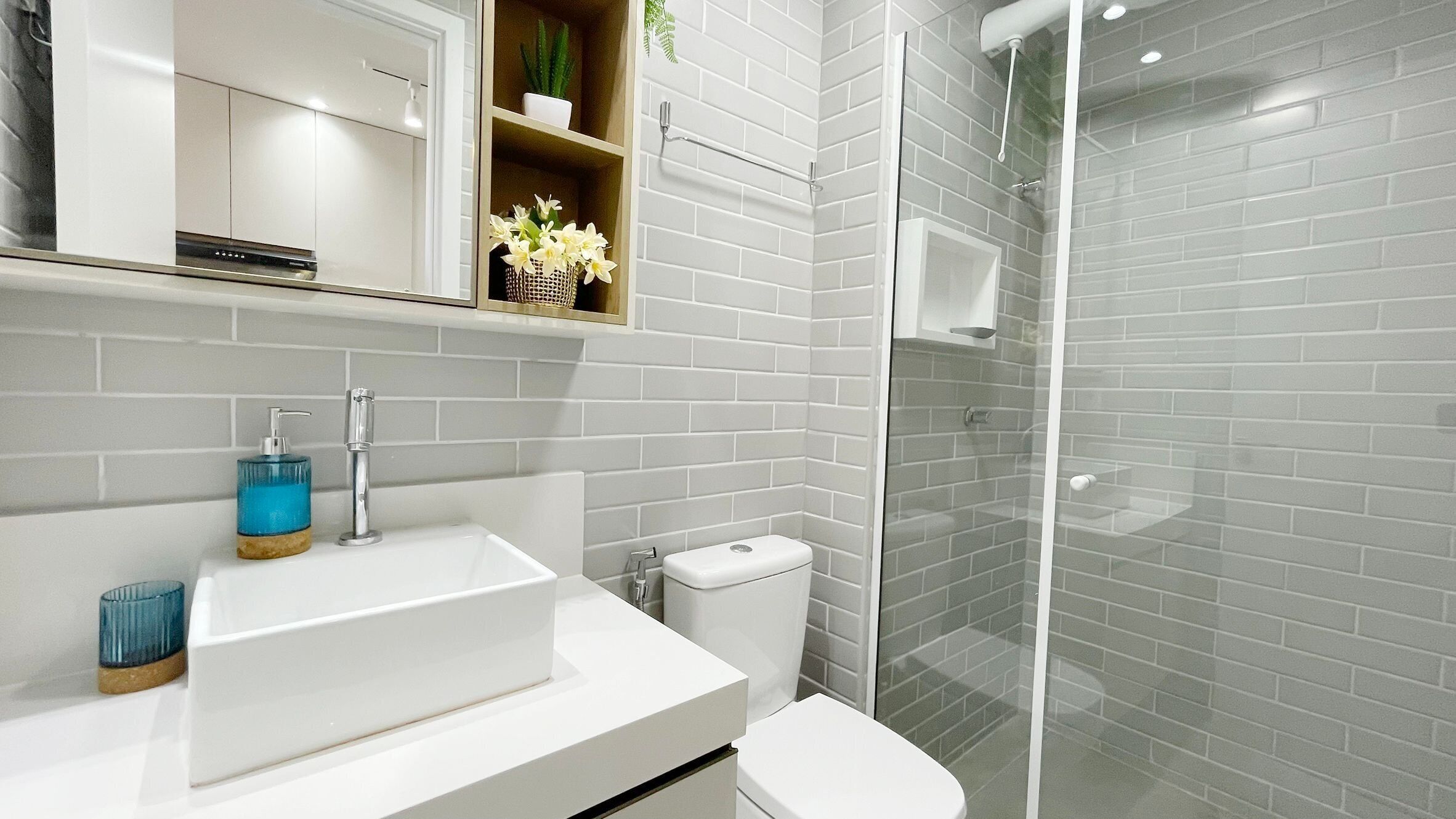 A modern bathroom with a white sink, toilet, and glass shower enclosure.