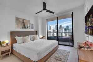 A modern bedroom with a large bed, a city view balcony, and a ceiling fan. - Bright & Breezy 1 Bed Unit With Water & City Views (Miami)