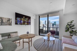 A modern living room with a cityscape view, a round coffee table, and a sofa. - Bright & Breezy 1 Bed Unit With Water & City Views (Miami)