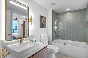 A modern bathroom with a large mirror, two sinks, a toilet, and a bathtub. - Bright & Breezy 1 Bed Unit With Water & City Views (Miami)