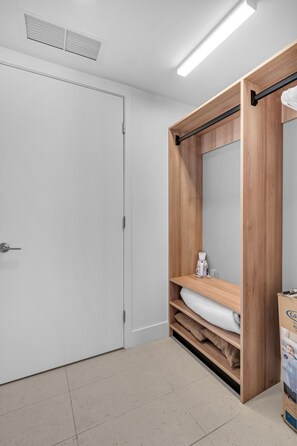 A bathroom with a white door, a wooden vanity with a mirror, and a towel rack. - Bright & Breezy 1 Bed Unit With Water & City Views (Miami)