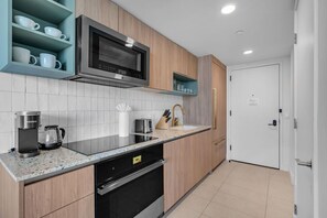 A modern kitchen with a built-in microwave, coffee maker, and dishwasher. - Bright & Breezy 1 Bed Unit With Water & City Views (Miami)