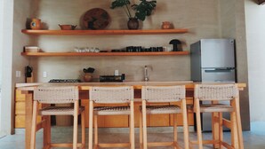 A kitchen with wooden chairs, a sink, and a refrigerator. - Casa Boga - Comfortable designer house in La Punta (Brisas de Zicatela)
