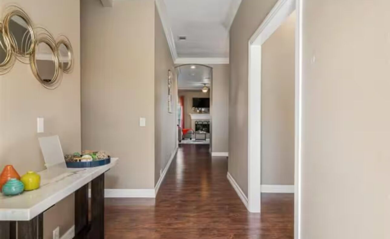 A hallway with a marble countertop, decorative mirrors, and a wooden floor.