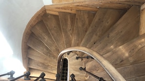 A wooden spiral staircase with metal handrails and decorative balusters.