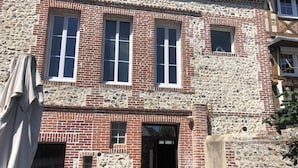 A building with a stone facade and red brick lower section, featuring multiple windows and a visible entrance.