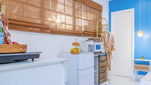 Une cuisine moderne avec des appareils électroménagers blancs, un four à micro-ondes et un panier de fruits.