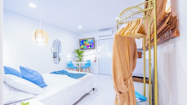 Une chambre d’hôtel moderne, équipée d’un lit, d’une table de chevet et d’un fauteuil suspendu.