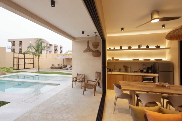 A modern kitchen with a built-in microwave, a refrigerator, and a dining area with a wooden table and chairs.