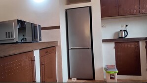 A compact kitchen with a refrigerator, microwave, and a kettle on the countertop. - 3-bedroom villa in gorgeous Ngaparou with WiFi, AC, 10 min. away from the beach (Ngaparou)