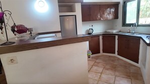 A kitchen with a built-in refrigerator, wooden cabinets, a sink, and a window. - 3-bedroom villa in gorgeous Ngaparou with WiFi, AC, 10 min. away from the beach (Ngaparou)