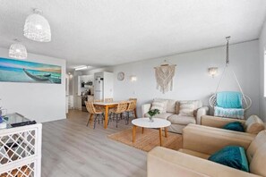 Una sala de estar moderna con comedor, una silla colgante y una cocina al fondo.
