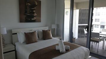 Habitación de hotel moderna con una cama grande, vistas al exterior y un cuadro en la pared.