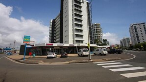 A multi-story building with a modern design, a visible storefront, and a street corner with parked cars and a pedestrian crossing. - Maroochy Sands (Sunshine Coast)