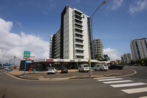 A multi-story building with a modern design, a visible storefront, and a street corner with parked cars and a pedestrian crossing. - Maroochy Sands (Sunshine Coast)