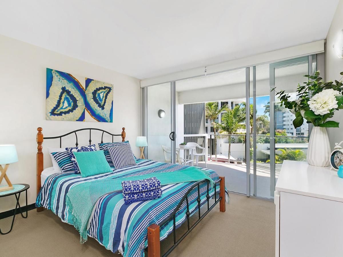 Un dormitorio moderno con una cama grande, un balcón con vistas y un aparador blanco.