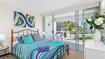 Un dormitorio moderno con una cama grande, un balcón con vistas y un aparador blanco.