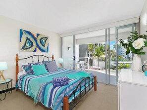 Un dormitorio moderno con una cama grande, un balcón con vistas y un aparador blanco.