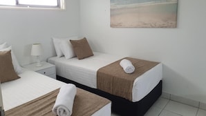 A hotel room with two beds, a window, a painting of a beach, and a nightstand with a lamp. - Maroochy Sands (Sunshine Coast)