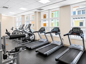 Une salle de sport équipée de tapis de course, de vélos elliptiques et d’appareils de musculation.