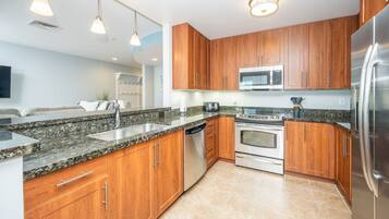 Een magnetron, een vaatwasser, kookgerei, borden en bestek, eettafels